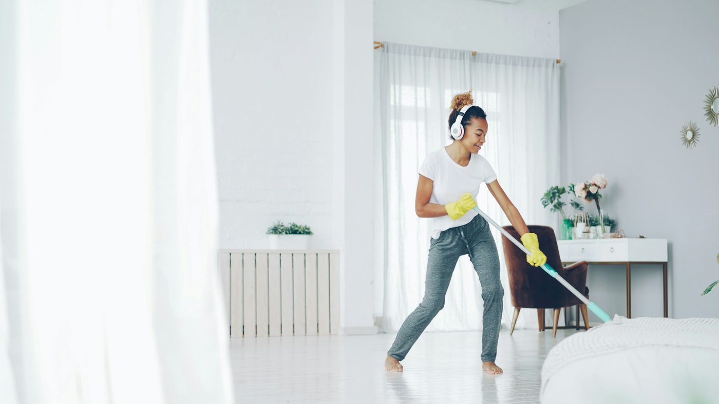 Woman with headphones happily cleaning a bright room