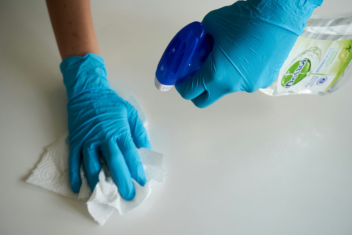 Gloved hands wiping a white surface